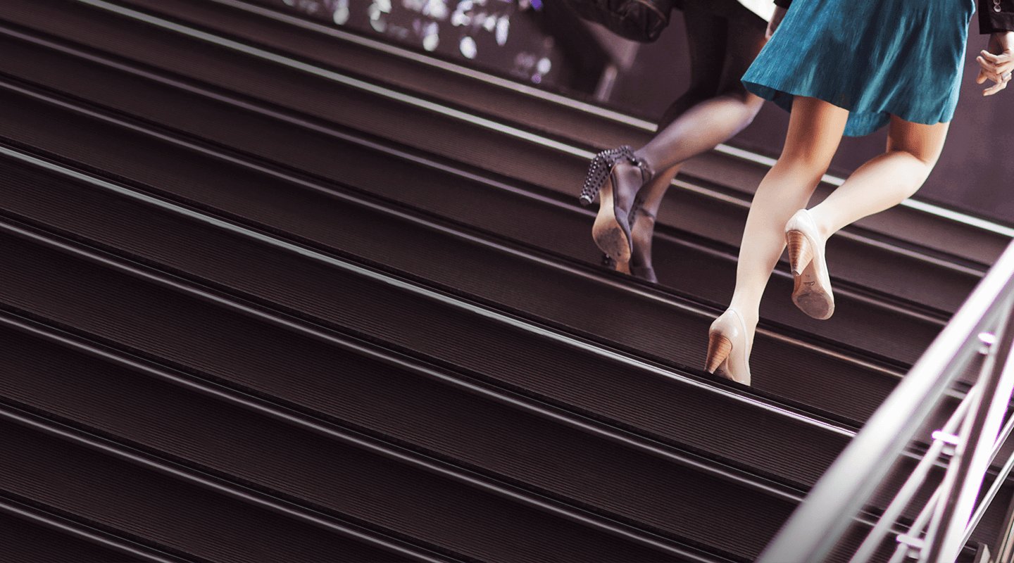 Photo of women’s legs as they walk up stairs.