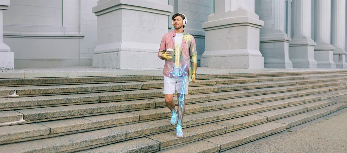 Man walking down outdoor steps, with an anatomy overlay showing the spine, pelvis, arm, and leg.