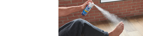 Man using Dr. Scholl's foot spray on bare foot